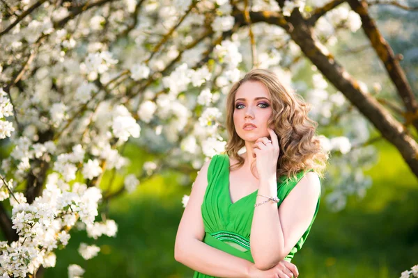 Bella giovane donna bionda in piedi accanto a un albero di mele in fiore — Foto Stock