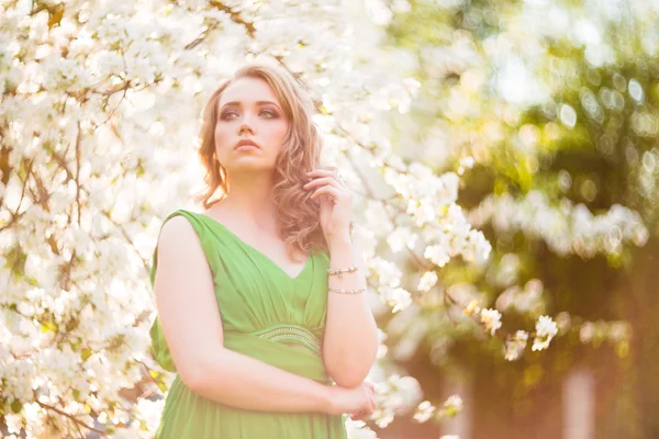 Bella giovane donna bionda in piedi accanto a un albero di mele in fiore — Foto Stock