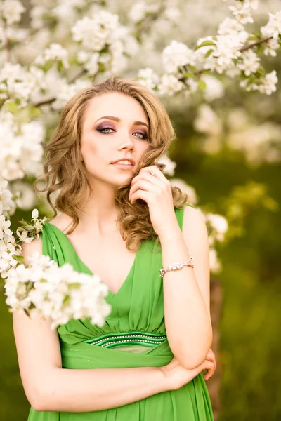 Bella giovane donna bionda in piedi accanto a un albero di mele in fiore — Foto Stock