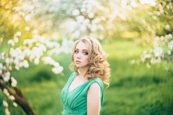 Bella giovane donna bionda in piedi accanto a un albero di mele in fiore — Foto Stock