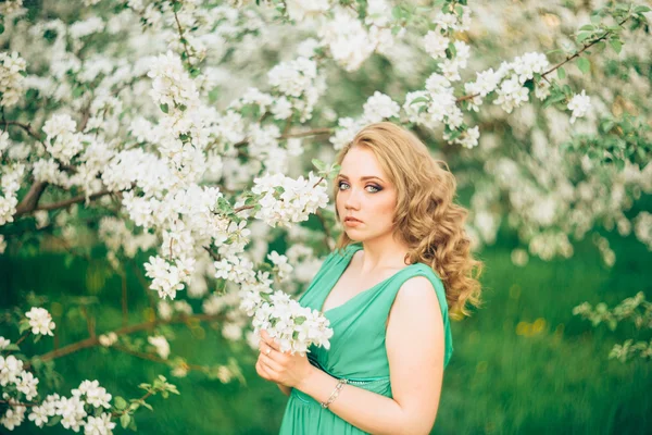 Bella giovane donna bionda in piedi accanto a un albero di mele in fiore — Foto Stock