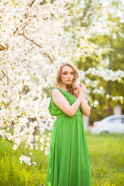 Bella giovane donna bionda in piedi accanto a un albero di mele in fiore — Foto Stock