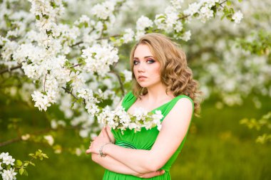 Şu yeni gelişen bir elma ağacı duran güzel genç sarışın kadın