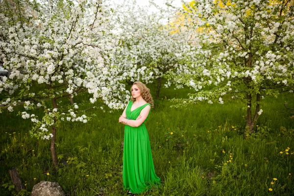 Schöne junge blonde Frau steht neben einem blühenden Apfelbaum — Stockfoto