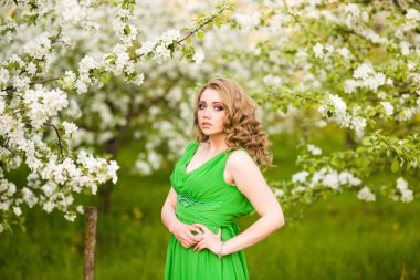 Şu yeni gelişen bir elma ağacı duran güzel genç sarışın kadın