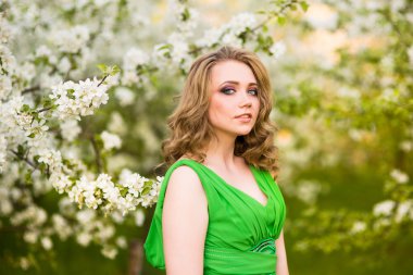 Şu yeni gelişen bir elma ağacı duran güzel genç sarışın kadın