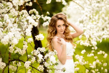 Çiçek açan bir elma meyve bahçesinde Bahar güzel kız ayakta, Sarışın, .