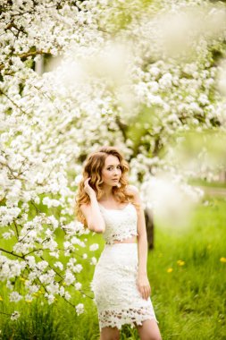 Çiçek açan bir elma meyve bahçesinde Bahar güzel kız ayakta, Sarışın, .