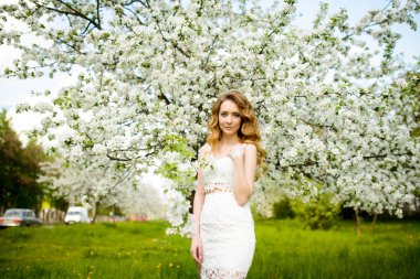 Çiçek açan bir elma meyve bahçesinde Bahar güzel kız ayakta, Sarışın, .