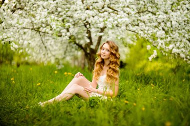 Çiçek açan bir elma meyve bahçesinde Bahar güzel kız ayakta, Sarışın, .