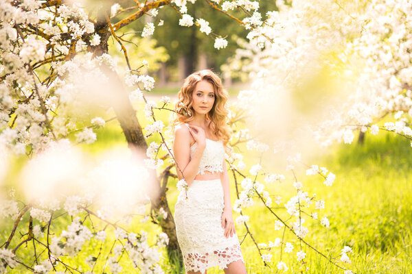 Spring beautiful romantic girl, blonde, standing in a blooming Apple orchard .