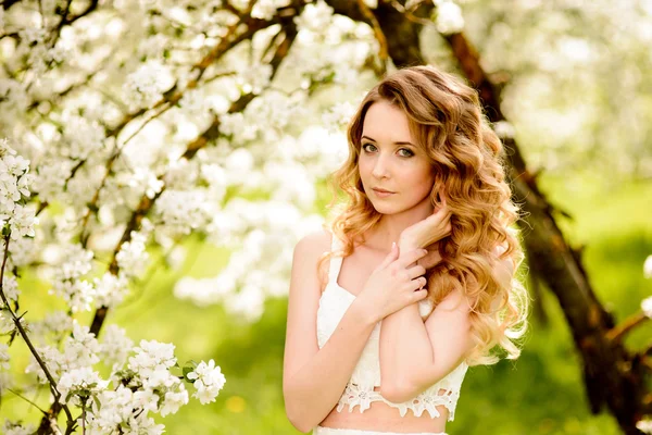 Primavera menina bonita, loira, de pé em um pomar de maçã florescendo  . — Fotografia de Stock