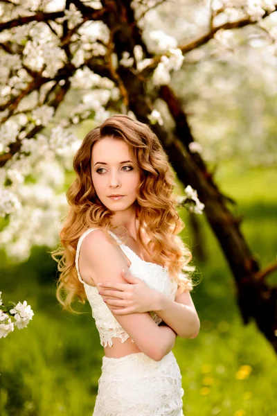 Tavasszal szép lány, szőke, állva egy virágzó Alma gyümölcsös . — Stock Fotó