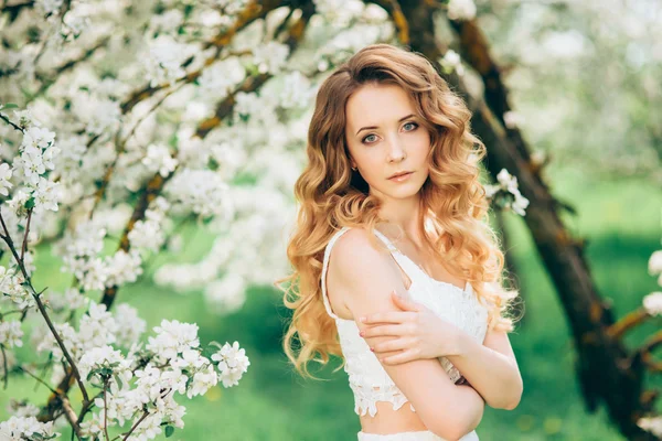 Primavera menina bonita, loira, de pé em um pomar de maçã florescendo  . — Fotografia de Stock