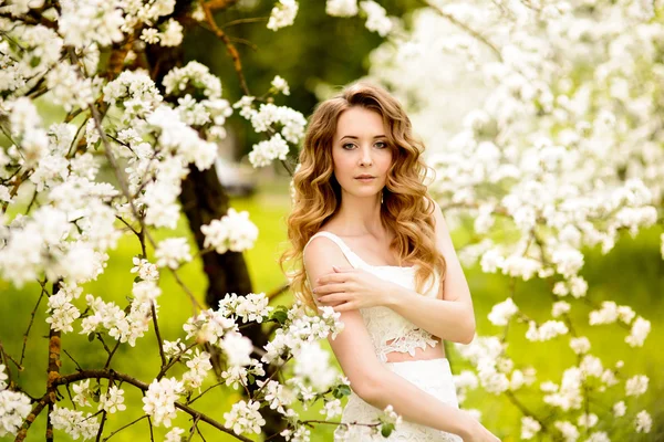 Frühling schöne Mädchen, blond, steht in einem blühenden Apfelgarten . — Stockfoto