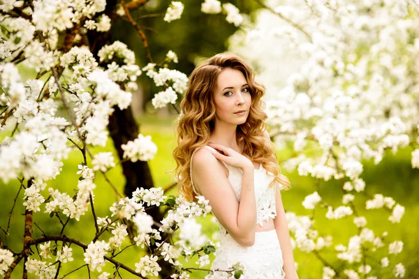 Primavera menina bonita, loira, de pé em um pomar de maçã florescendo  . — Fotografia de Stock