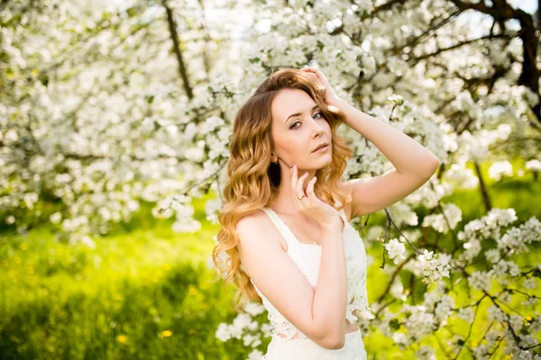 Vårens vackra flicka, Blond, stående i en blommande äppelträdgård . — Stockfoto