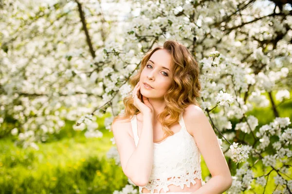 Primavera bella ragazza, bionda, in piedi in un frutteto di mele in fiore  . — Foto Stock