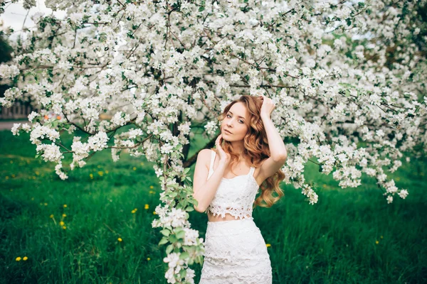 Lente mooi meisje, blond, permanent in een bloeiende boomgaard van Apple . — Stockfoto