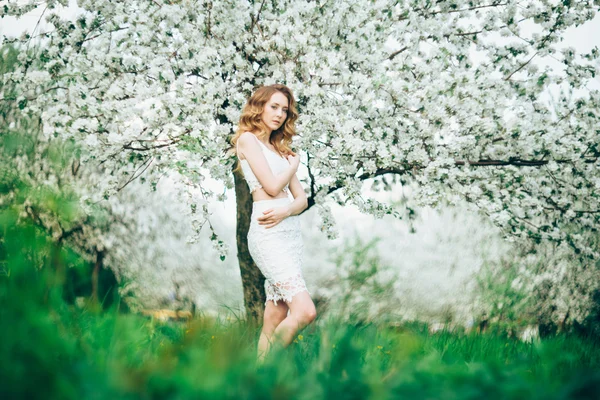 Printemps belle fille, blonde, debout dans un verger de pommes en fleurs  . — Photo