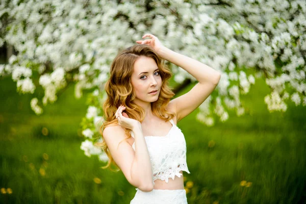 Chica hermosa primavera, rubia, de pie en un huerto de manzanas en flor  . — Foto de Stock