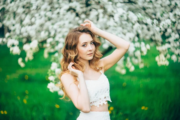 Primavera menina bonita, loira, de pé em um pomar de maçã florescendo  . — Fotografia de Stock