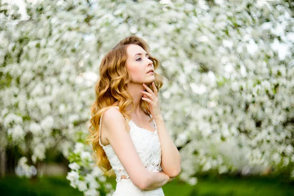 Jaro krásná holka, blond, stojící v kvetoucí jabloňový sad . — Stock fotografie