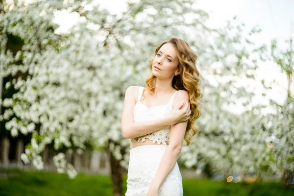 Primavera bella ragazza, bionda, in piedi in un frutteto di mele in fiore  . — Foto Stock