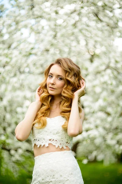 春の美しい少女、金髪、咲くリンゴ園に立っています。 . — ストック写真