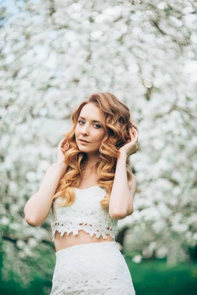 Vårens vackra flicka, Blond, stående i en blommande äppelträdgård . — Stockfoto