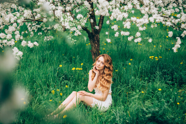 Spring beautiful romantic girl, blonde, standing in a blooming Apple orchard .