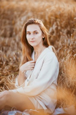 Buğday tarlasında modellik yapan bir kızın portresi. Güneşli bir günde buğday tarlasında oturan bir kız.