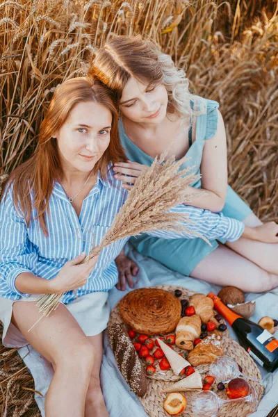 Щасливі друзі в пшеничному полі. дівчата на пікніку в полі на заході сонця . — стокове фото