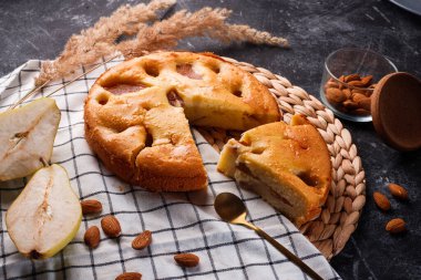 Siyah metal arka planda ev yapımı armut turtası ve beyaz masa örtüsü.