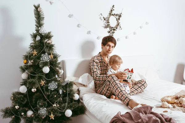 Baba Oğul Evde Noel Ağacının Yanındaki Yatakta Eğleniyorlar — Stok fotoğraf