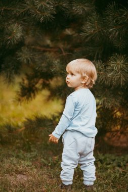 Mavi elbiseli güzel bir çocuk bir sonbahar günü parkta birine gülümsüyor ve yürüyor.