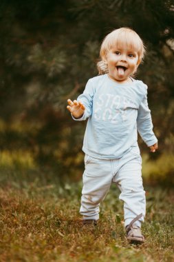 Mavi elbiseli güzel bir çocuk bir sonbahar günü parkta birine gülümsüyor ve yürüyor.