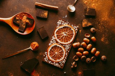 Portakallı çikolata. Baharatlar yüzeye serpilmiş, turuncu sitron ve koyu kahverengi arka planda koyu çikolata parçaları. Üst görünüm, kopyalama alanı