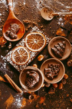 Noel Baba, Noel Baba, Noel ağacı, çanlar, mum, siyah masada portakal ve baharatlı çikolatanın yanında.