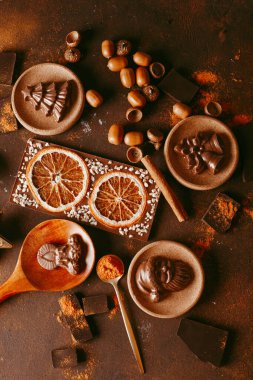 Çikolatayla yapılmış çeşitli Noel heykelcikleri arka planda, çatal bıçak ve baharatların yanında duruyor.