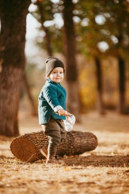 Sonbaharda yürüyüşe çıkan bir çocuk. Yeşil ceketli bir çocuk sonbaharın arka planında parkta yürüyor.