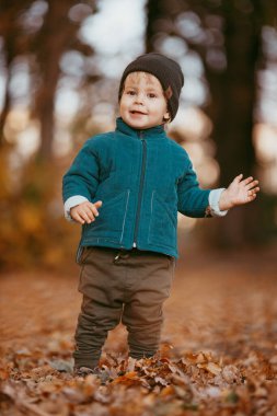 Mutlu çocuk geliyor. Yeşil ceketli ve kahverengi pantolonlu bir çocuk. Seçici odaklı resim.