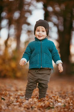 Mutlu çocuk geliyor. Yeşil ceketli ve kahverengi pantolonlu bir çocuk. Seçici odaklı resim.