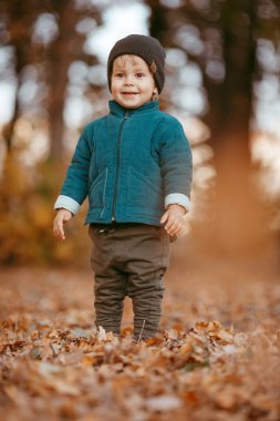 Mutlu çocuk geliyor. Yeşil ceketli ve kahverengi pantolonlu bir çocuk. Seçici odaklı resim.