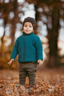 Mutlu çocuk geliyor. Yeşil ceketli ve kahverengi pantolonlu bir çocuk. Seçici odaklı resim.