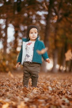 Mutlu çocuk geliyor. Yeşil ceketli ve kahverengi pantolonlu bir çocuk. Seçici odaklı resim.