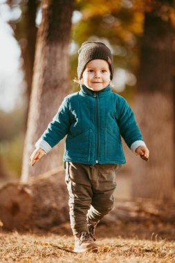 Neşeli çocuk koşuyor. Yeşil ceketli ve kahverengi pantolonlu bir çocuk. Seçici odaklı resim.