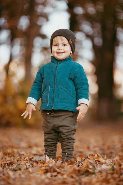 Viene el niño feliz. Un chico vestido con una chaqueta verde y pantalones marrones. — Foto de Stock