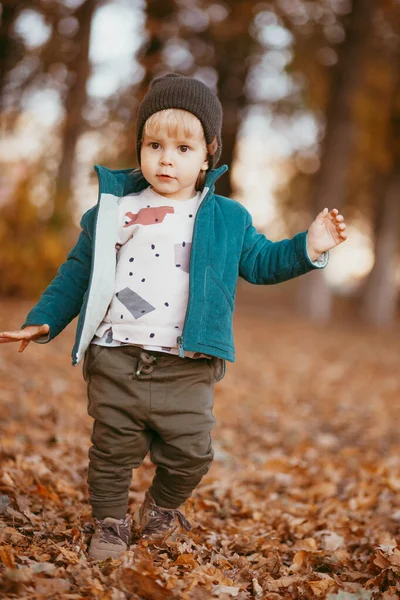 Radosne dziecko ucieka. Chłopiec ubrany w zieloną kurtkę i brązowe spodnie.. — Zdjęcie stockowe