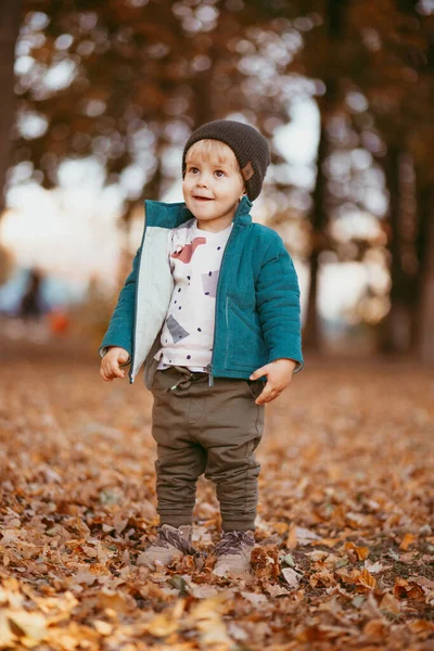Jön a boldog gyermek. Egy fiú zöld kabátban és barna nadrágban.. — Stock Fotó